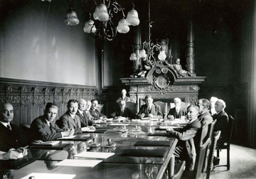 Photographie noir et blanc montrant 14 hommes autour d'une grande table de travail. On reconnaît Albert Châtelet siégeant en bout de table.