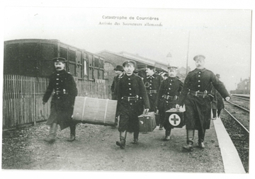 Carte postale noir et blanc montrant des hommes portant des caisses sur un quai de gare.