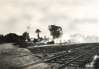 Photographie noir et blanc montrant des rails de chemin de fer disparaissant sous une épaisse fumée.