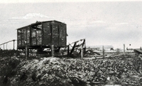 Photographie noir et blanc montrant un wagon endommagé au milieu de gravas.