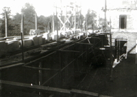 Photographie noir et blanc montrant des échafaudages autour d'une construction en travaux.
