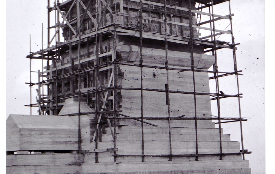 Photographie noir et blanc montrant un édifice en travaux, entouré d'un échaffaudage.