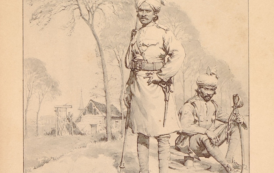 Deux soldats de la cavalerie indienne, dont l’un est équipé d’éperons et l’autre d’un sabre, posent devant ce qui semble être une ferme et un bois.