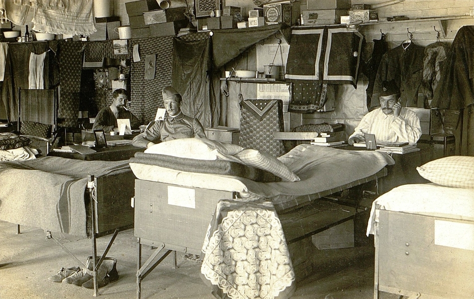 Photographie noir et blanc montrant trois hommes assis dans un dortoir.