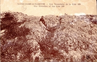 Carte postale sepia montrant un homme sortant d'une tranchée creusée dans le flanc d'une colline.