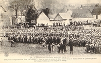 Carte postale noir et blanc montrant une centaine d'hommes rassemblés derrière des barbelés.