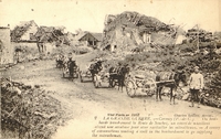 Carte postale noir et blanc montrant une caravane de munitions traversant un village dont il ne reste que des ruines.
