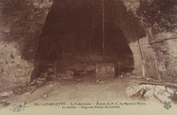 Carte postale noir et blanc montrant l'entrée d'un abri creusé dans la roche.