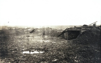 Photographie noir et blanc montrant un champ détrempé d'où émergent quelques débris de constructions en bois.