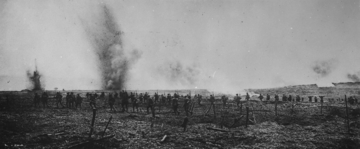 Photographie noir et blanc montrant des soldats s'élançant sur un champ de bataille bombardé.