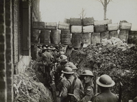 Photographie noir et blanc montrant des soldats dans une tranchée protégée par des tonneaux.