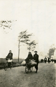 Photographie noir et blanc montrant des hommes, des femmes et des enfants sur les routes, chargés de lourds bagages et parfois à vélo.