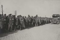 Photographie noir et blanc montrant un convoi d'hommes marchant sur une route.