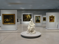 Photographie couleur montrant une salle de musée, avec au premier plan, une statue d'un homme en pied.