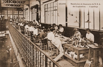 Carte postale en noir et blanc d'un atelier de manufacture où l'on voit un groupe d'ouvrières penchées sur leur ouvrage.
