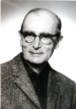 Photographie noir et blanc de Pierre Lesdain esquissant un léger sourire et portant les lunettes.