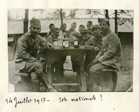 Photographie noir et blanc montrant des soldats regroupés autour d'une table sur laquelle sont disposées des bouteilles et des verres.