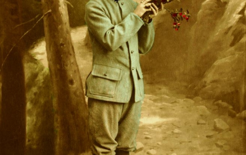 Carte postale couleur d'un homme en habit de soldat tenant un bouquet de fleurs au détour d'un chemin boisé.